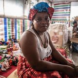 Tene sitzt in ihrem Landen und schaut in die Kamera.