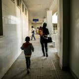 World Press Photo: Eine Frau und ein kleiner Junge von hinten, sie laufen einen gefliesten Gang entlang