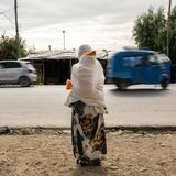 World Press Photo: Eine Frau wartet mit einem Kind auf dem Rücken am Straßenrand