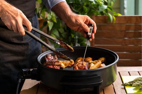 Mann nutzt ein smartes Fleischthermometer beim Grillen.