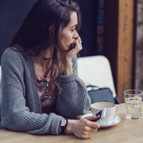 Eine junge Frau sitzt nachdenklich am Tisch