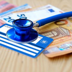 Stethoskop und Gesundheitskarte liegen auf einigen Euro-Banknoten