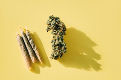 Drei gedrehte Joints liegen neben einer dicken Cannabis-Blüte