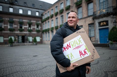 Alex Liefermann steht mit Plakat auf Marktplatz in Düsseldorf