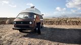 Joy steht an ihrem Van gelehnt am Strand