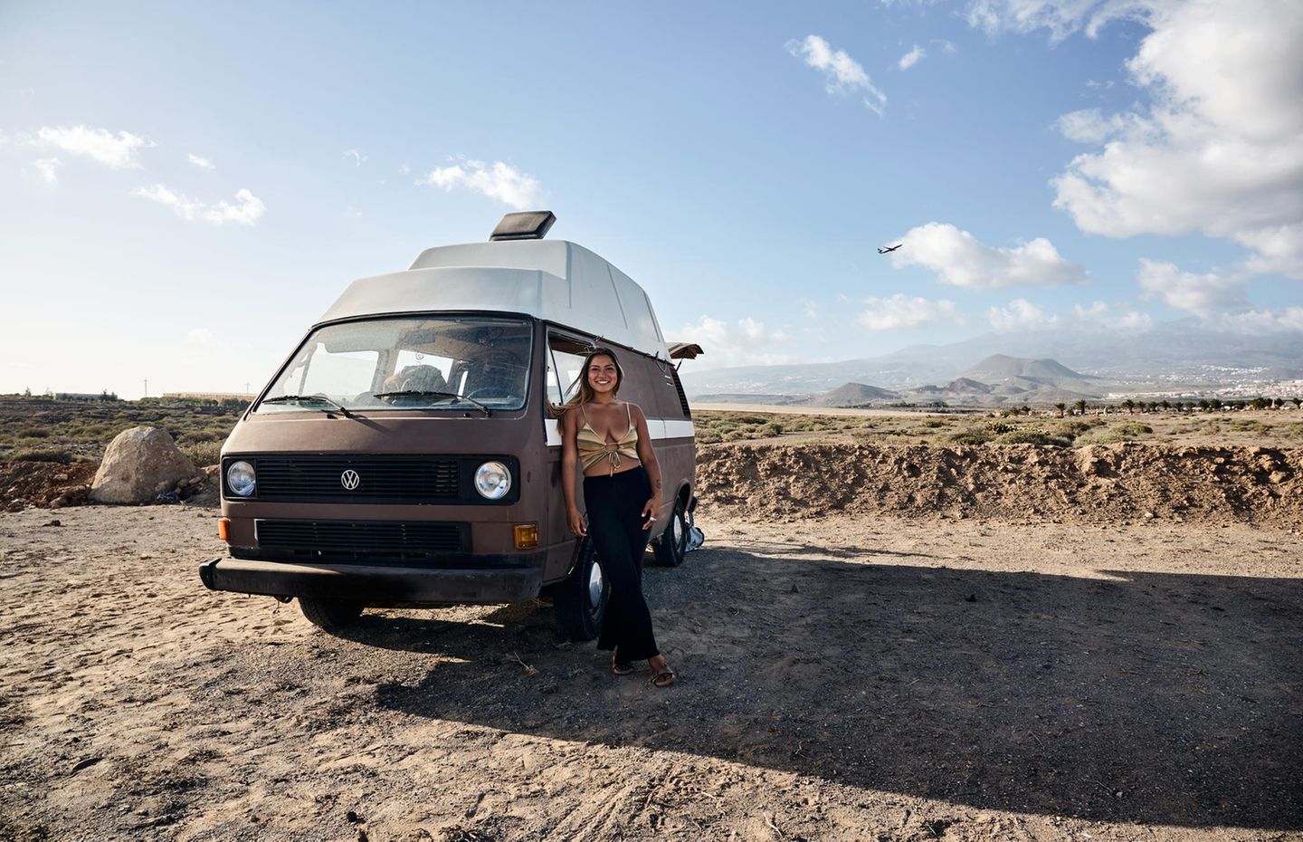 Joy steht an ihrem Van gelehnt am Strand Joy steht an ihrem Van gelehnt am Strand