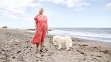 Moni und ihr weißer Hund stehen am Strand