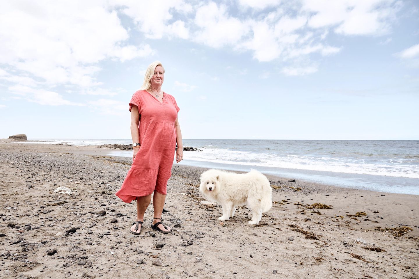 Moni und ihr weißer Hund stehen am Strand