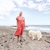 Moni und ihr weißer Hund stehen am Strand