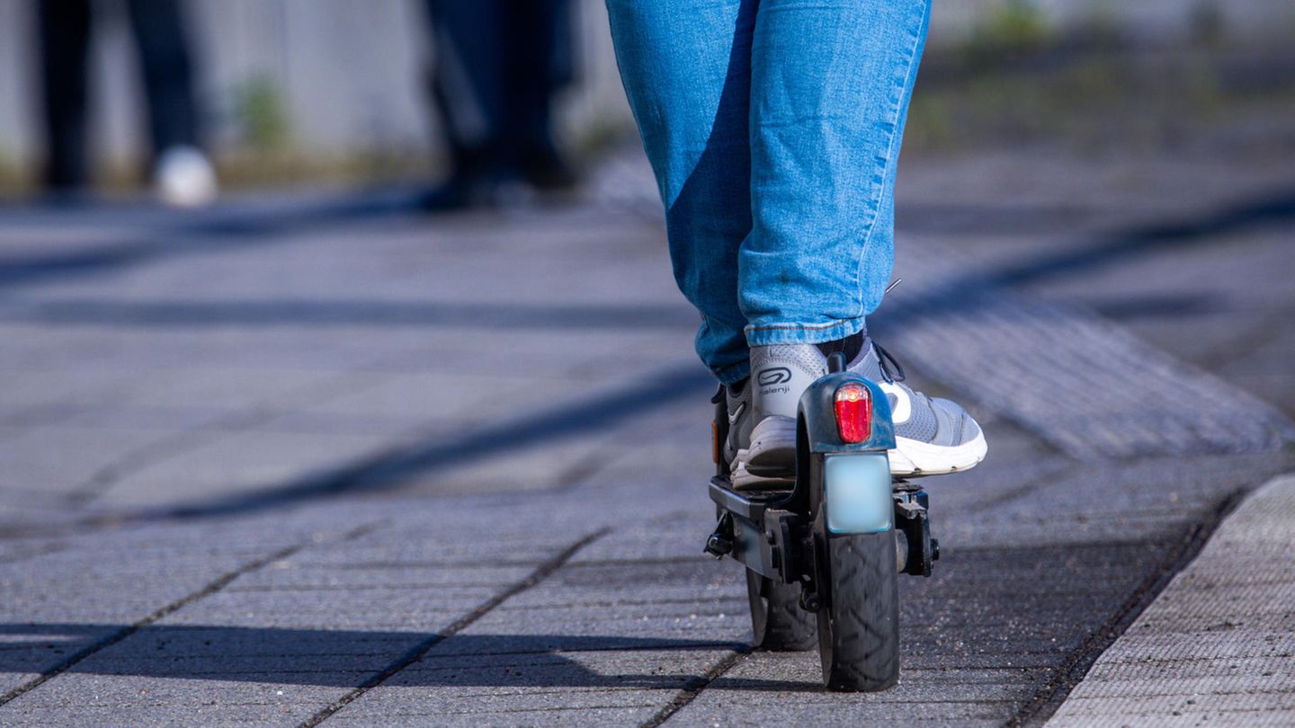 Die Beine eines Jugendlichen stehen auf einem E-Scooter