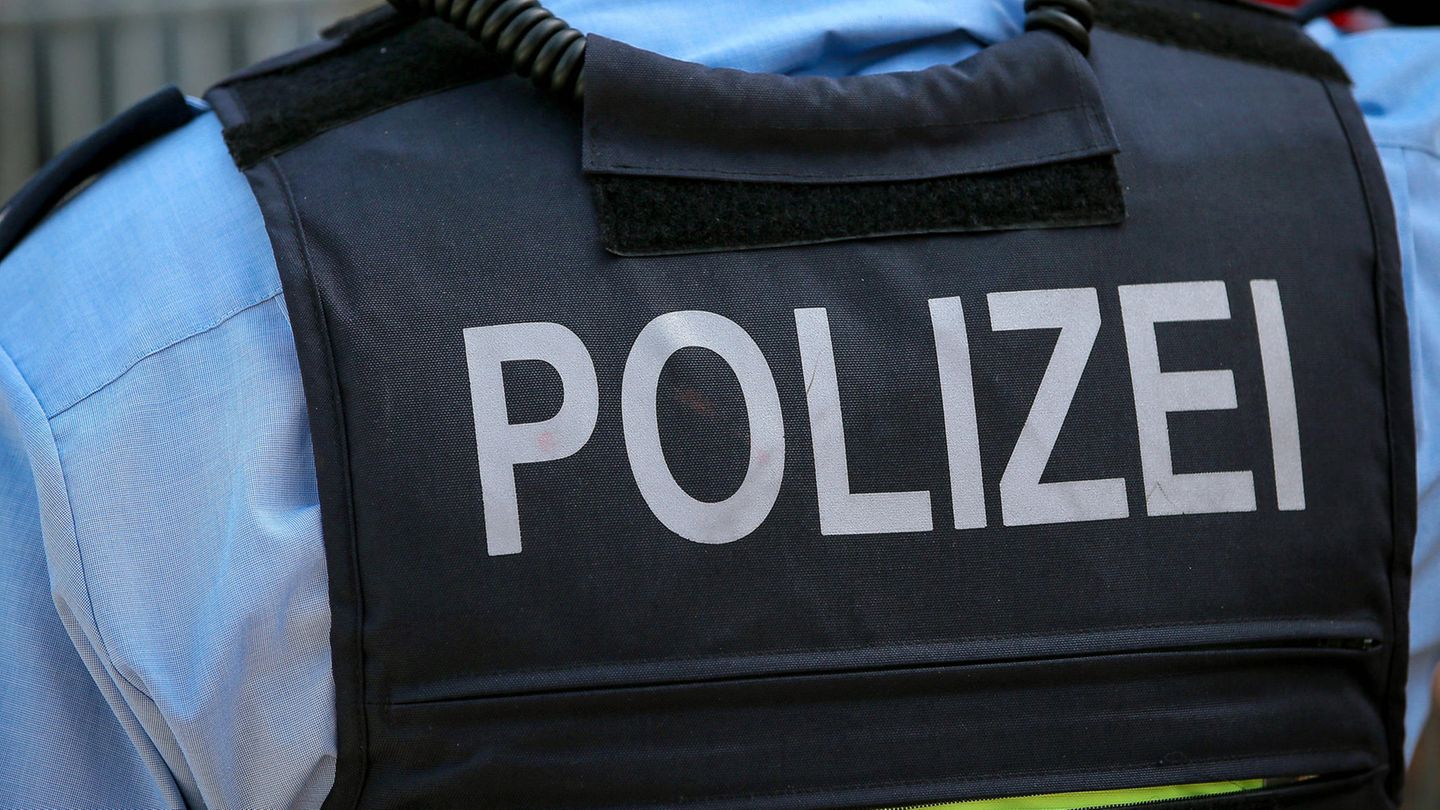 Ein Polizist von hinten in Weste und mit blauem Hemd, Rassismus ist ihm verboten