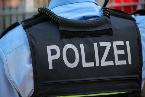 Ein Polizist von hinten in Weste und mit blauem Hemd, Rassismus ist ihm verboten