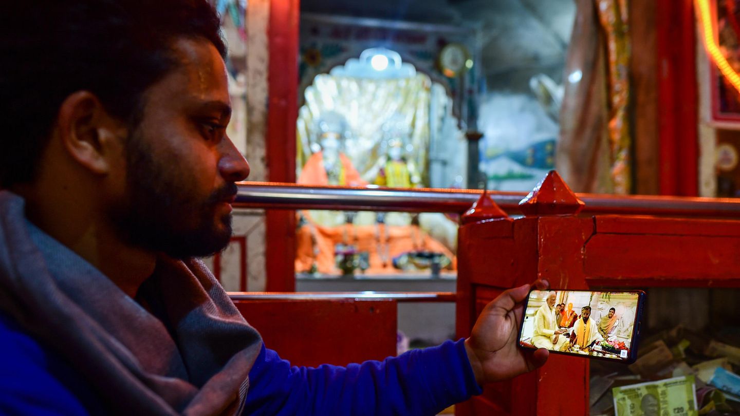 Ein Mann im indischen Ayodhya sieht sich die Einweihungszeremonie aus einem Hindu-Tempel per Livestream auf dem Handy an Ein Mann im indischen Ayodhya sieht sich die Einweihungszeremonie aus einem Hindu-Tempel per Livestream auf dem Handy an