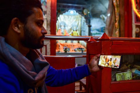 Ein Mann im indischen Ayodhya sieht sich die Einweihungszeremonie aus einem Hindu-Tempel per Livestream auf dem Handy an
