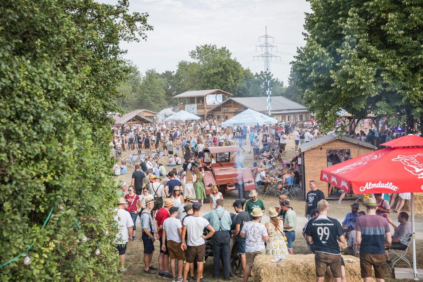 Brass Wiesn Festival: das Woodstock der Blasmusik Ein ländliches Festivalgelände im Grünen. Manche Menschen tragen eine Tracht.