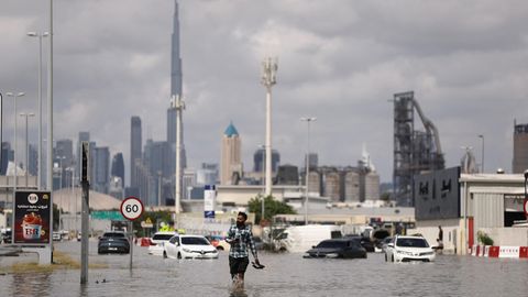Ein Mensch läuft durch die gefluteten Straßen. Im Hintergrund der Burj Khalifa, das höchste Gebäude der Welt.
