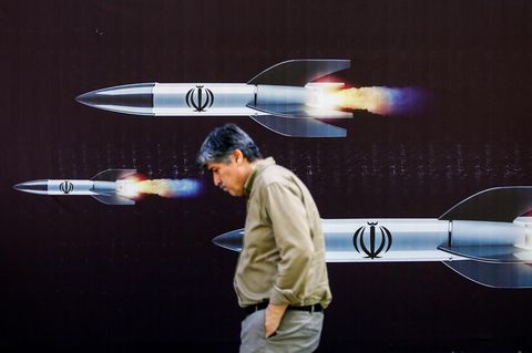Ein Mann in Teheran läuft vor einem Plakat iranischer Raketen
