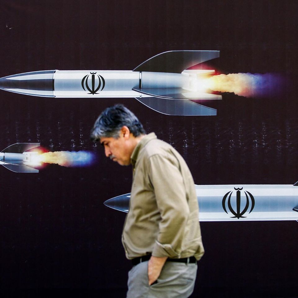 Ein Mann in Teheran läuft vor einem Plakat iranischer Raketen
