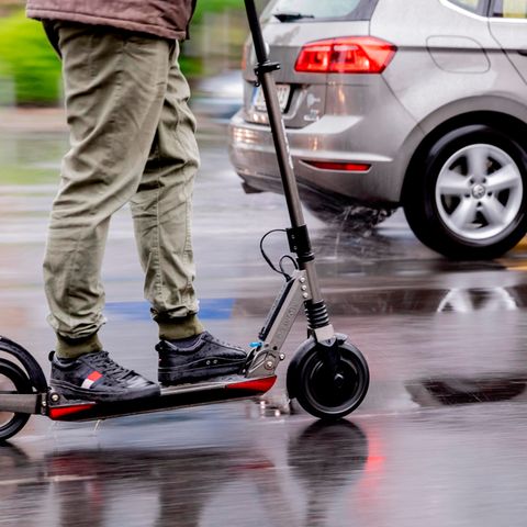 Ein Mann auf einem E-Scooter auf nasser Straße