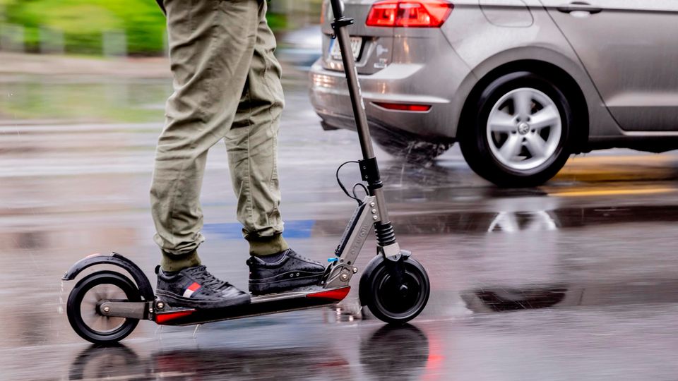 Ein Mann auf einem E-Scooter auf nasser Straße