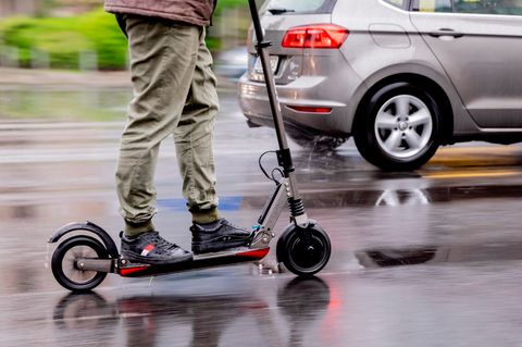 Ein Mann auf einem E-Scooter auf nasser Straße