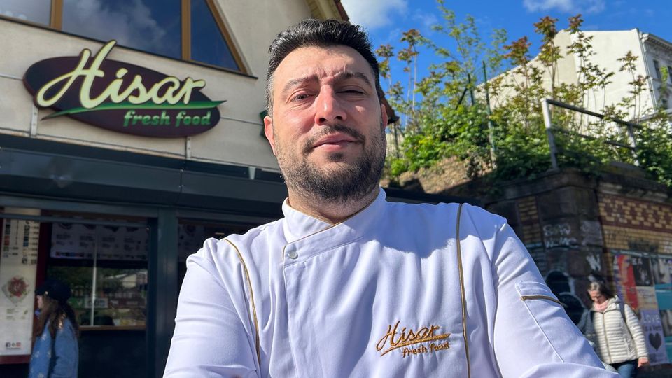 Imbissbetreiber Arif Keles steht in weißer Kochjacke vor seinem Dönerladen