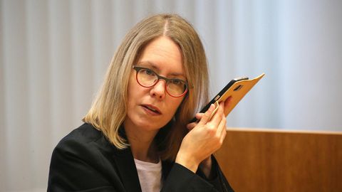 Anne Brorhilker, Oberstaatsanwältin, hört am Rande eines Prozesses um Cum-Ex-Deals im Landgericht in ihr Smartphone