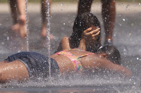 In Madrid kühlen sich Kinder an kleinen Wasserfontänen ab