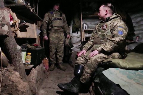 Ein ukrainischer Soldat mit Beinprothese sitzt aufs einem Bett im Schützengraben
