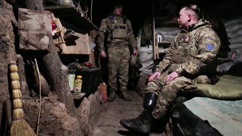 Ein ukrainischer Soldat mit Beinprothese sitzt aufs einem Bett im Schützengraben