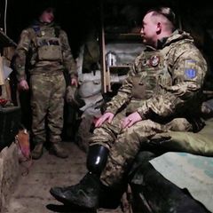 Ein ukrainischer Soldat mit Beinprothese sitzt aufs einem Bett im Schützengraben