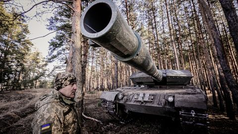 Leopard Panzer in der Ukraine in einem Wald, ein Ukrainischer Soldat steht davor
