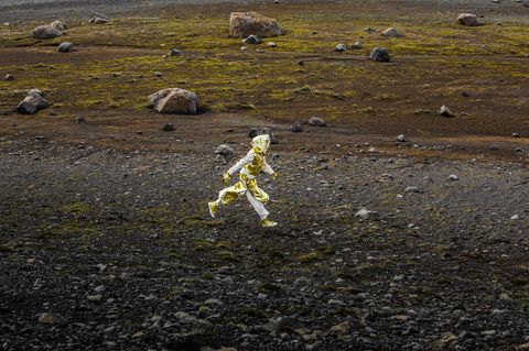 Ein Mensch in goldenem Outfit läuft durch eine karge Landschaft