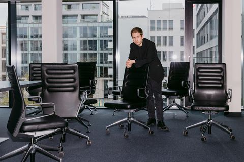 Kevin Kühnert steht in einem Büro zwischen vielen Bürostühlen