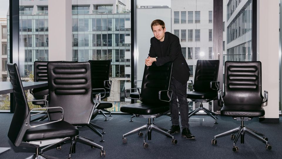 Kevin Kühnert steht in einem Büro zwischen vielen Bürostühlen