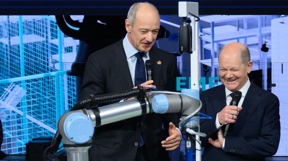 Bundeskanzler Olaf Scholz schaut sich am Stand von Siemens einen Roboter der Firma Schaeffler an