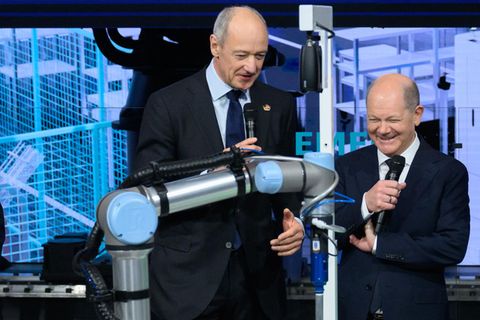 Bundeskanzler Olaf Scholz schaut sich am Stand von Siemens einen Roboter der Firma Schaeffler an