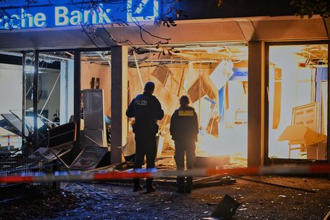 Polizisten stehen vor einer zerstörten Bankfiliale