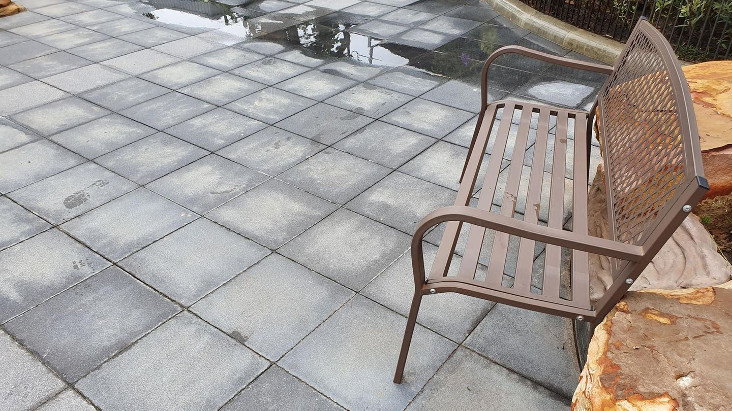Reinigung von Terrassenrissen mit Metallbesen von Unkraut
