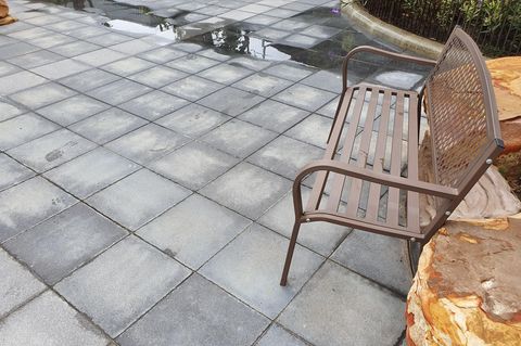 Reinigung von Terrassenrissen mit Metallbesen von Unkraut