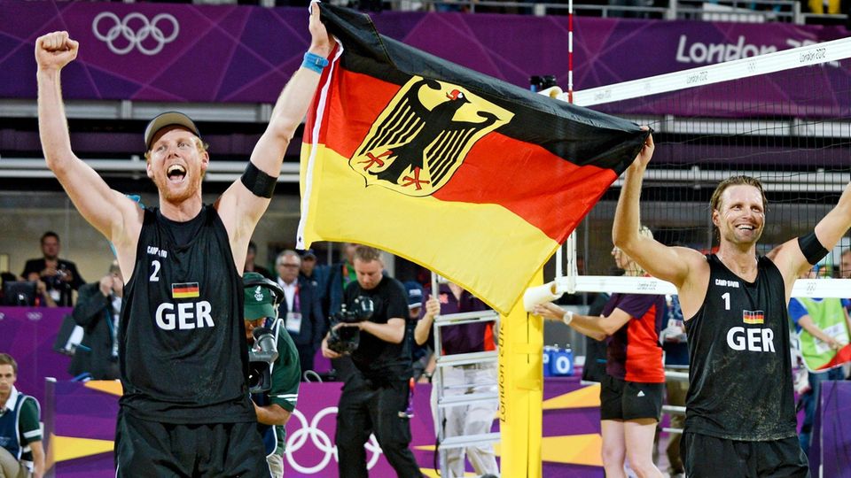 Jonas Reckermann (l.) und Julius Brink feiern ihren Olympiasieg in London 2012 mit einer Deutschlandfahne in der Hand