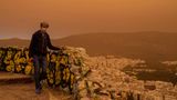 Dieser Mann versucht, sich mit einer Maske vor  dem Staub zu schützen. Zu recht: Der Griechische Pneumologen-Verband teilte mit, der afrikanische Staub enthalte selbst kleinste Partikel, die tief in die Lunge eindringen könnten. Insofern bietet eine OP-Maske wohl keinen perfekten Schutz, ist aber besser als nichts.