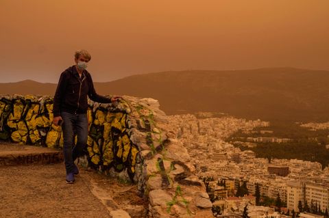Dieser Mann versucht, sich mit einer Maske vor  dem Staub zu schützen. Zu recht: Der Griechische Pneumologen-Verband teilte mit, der afrikanische Staub enthalte selbst kleinste Partikel, die tief in die Lunge eindringen könnten. Insofern bietet eine OP-Maske wohl keinen perfekten Schutz, ist aber besser als nichts.