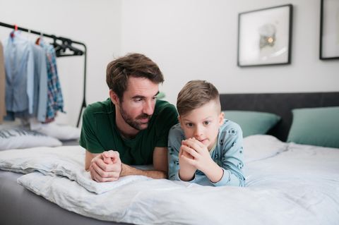 Ein Vater spricht mit seinem Sohn auf dem Bett.
