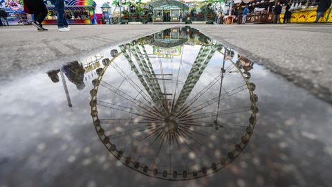 Ein Riesenrad spiegelt sich in einer Pfütze auf dem Festgelände des Stuttgarter Frühlingsfestes