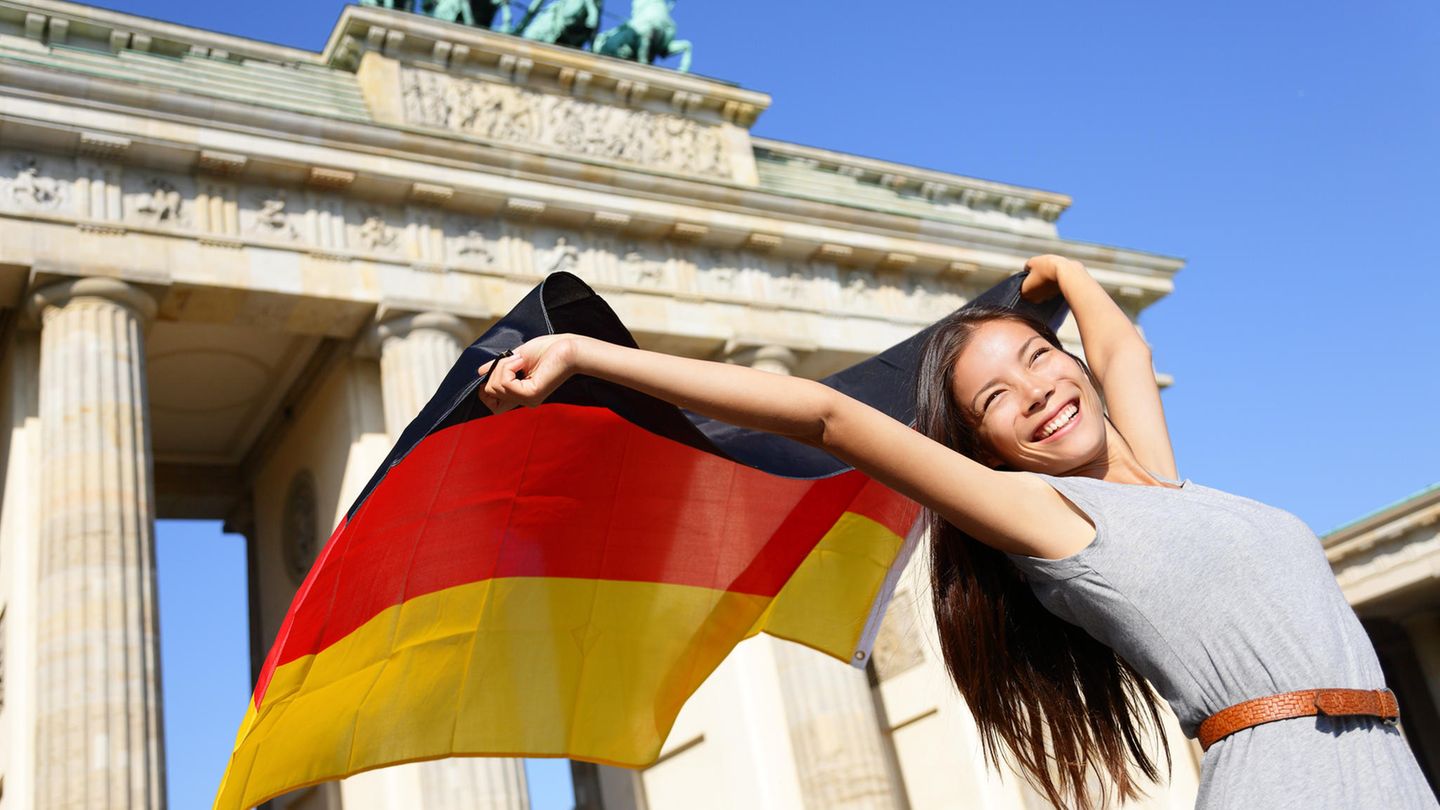 Junge Frau schwenkt die Deutschlandfahne vor dem Brandenburger Tor