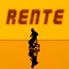 Person sitzt auf einem Rollator vor einer Leuchtwand mit der Aufschrift "Rente"