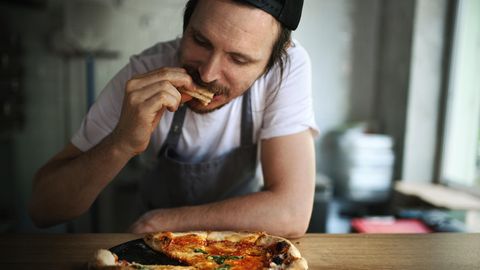 Ein Mann isst Pizza.