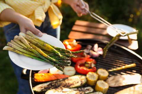 Spargel vom Grill: Grüner Spargel wird vom Grill auf einen Teller gelegt