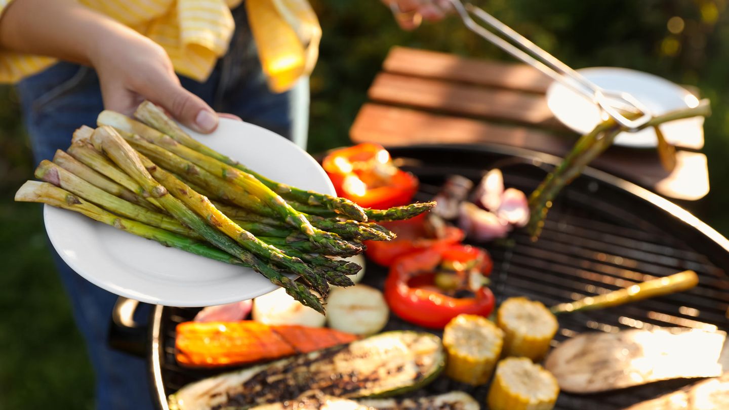 Spargel vom Grill: Grüner Spargel wird vom Grill auf einen Teller gelegt
